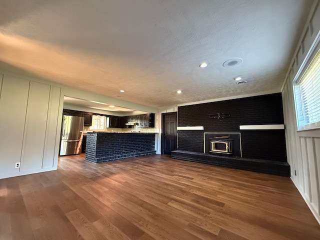 unfurnished living room with dark wood-type flooring, a textured ceiling, and a wealth of natural light