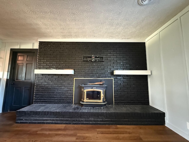 details featuring wood-type flooring, a textured ceiling, and a wood stove