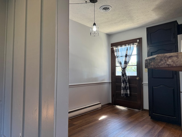 foyer entrance featuring dark hardwood / wood-style floors, baseboard heating, and a textured ceiling