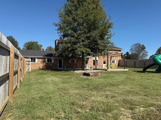 rear view of house with a yard and a playground