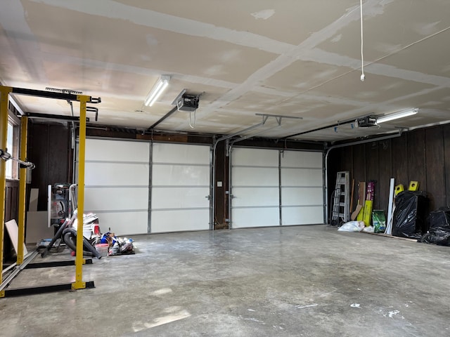 garage with a garage door opener and wood walls