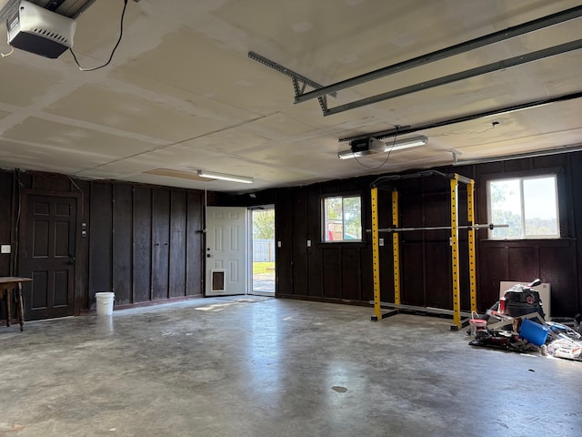 garage featuring a garage door opener and wooden walls