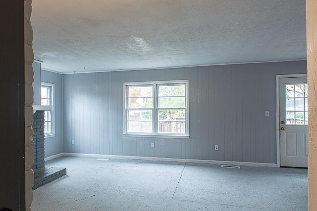 spare room with a brick fireplace and a textured ceiling