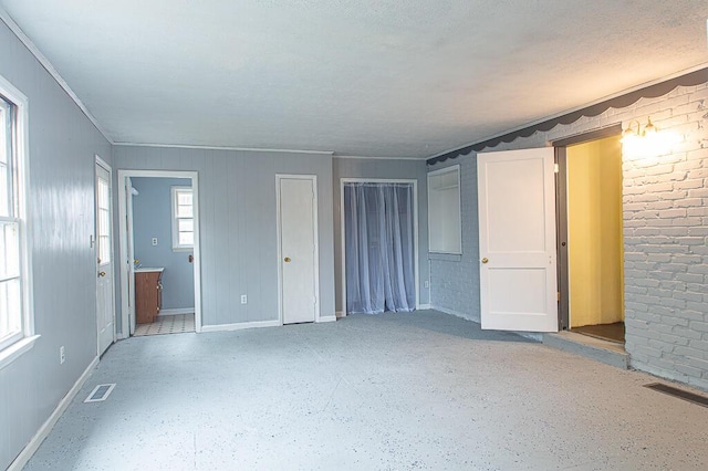 unfurnished bedroom with multiple closets, crown molding, and connected bathroom