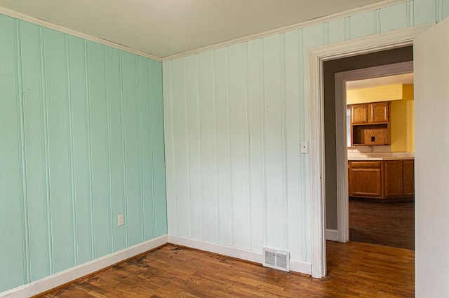 empty room with crown molding and dark hardwood / wood-style flooring