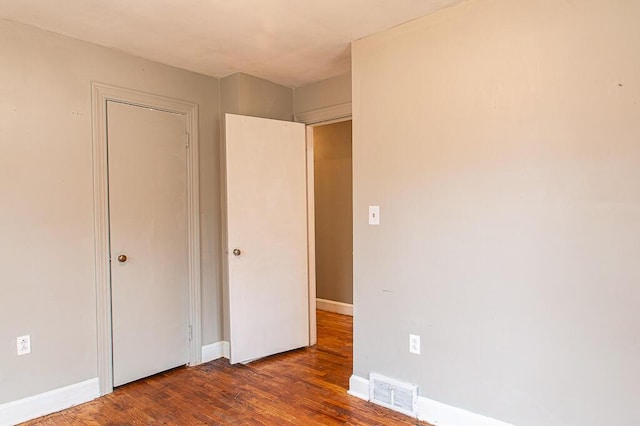 unfurnished bedroom featuring dark wood-type flooring and a closet