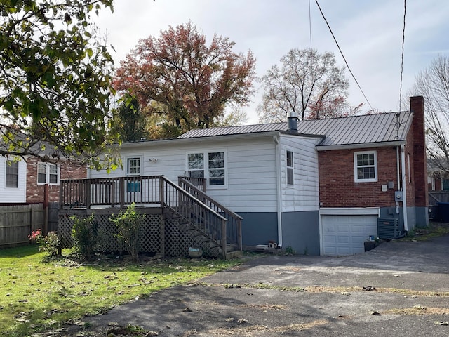 back of house featuring a garage, a wooden deck, and central air condition unit