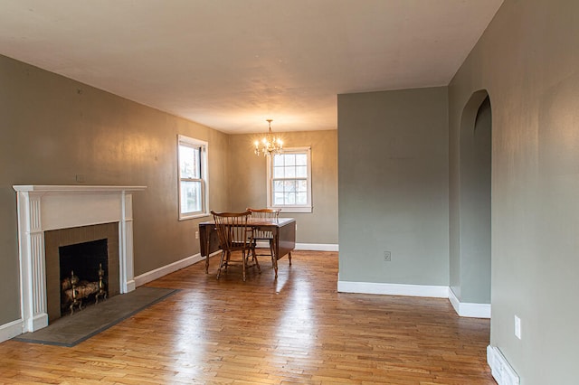 dining area with a chandelier, a tile fireplace, and light wood-type flooring