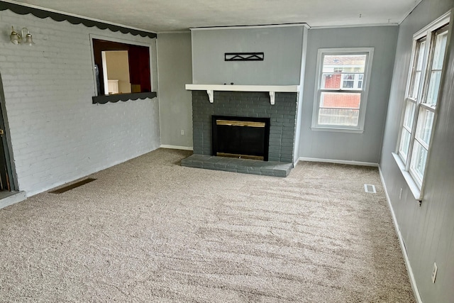 unfurnished living room with brick wall, ornamental molding, a brick fireplace, and light carpet