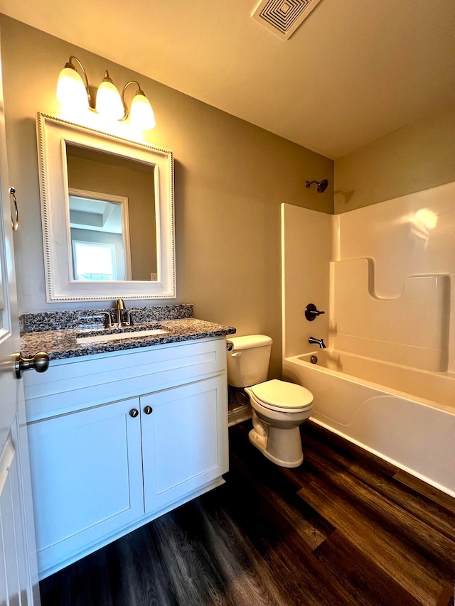 full bathroom with toilet, hardwood / wood-style floors, vanity, and washtub / shower combination