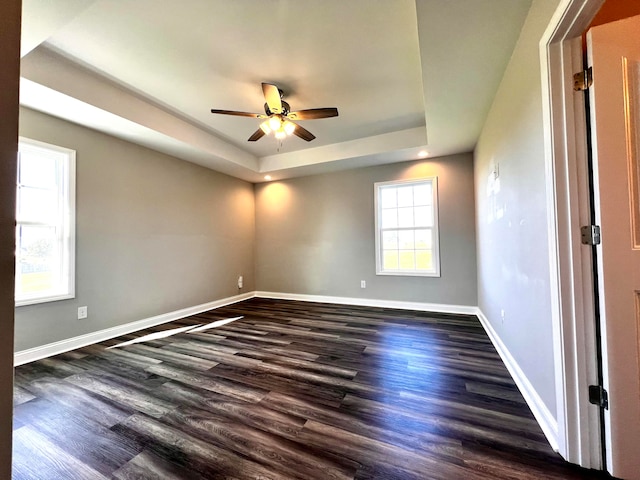 unfurnished room featuring dark hardwood / wood-style floors, a tray ceiling, and ceiling fan