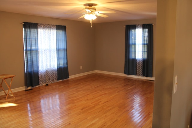 empty room with hardwood / wood-style floors, a wealth of natural light, and ceiling fan