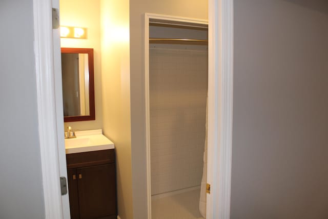 bathroom with a tile shower and vanity