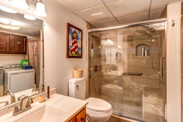 bathroom featuring a shower with door, vanity, washer / dryer, and toilet