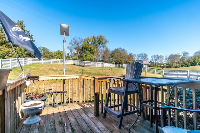 wooden deck with a rural view and a lawn