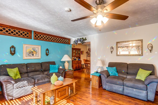 living room with ceiling fan, wood-type flooring, and a textured ceiling