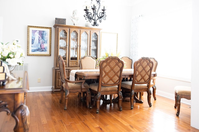 dining space featuring wood-type flooring and an inviting chandelier