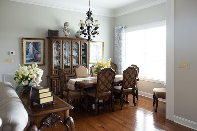 dining area with hardwood / wood-style flooring, a healthy amount of sunlight, ornamental molding, and a chandelier