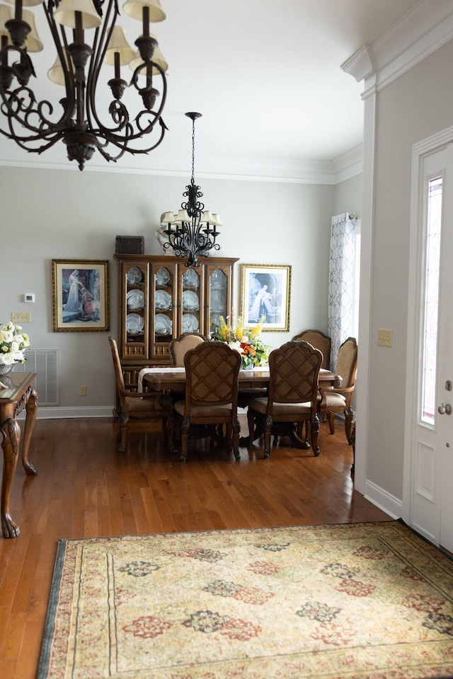 dining space with an inviting chandelier, crown molding, a healthy amount of sunlight, and dark hardwood / wood-style flooring