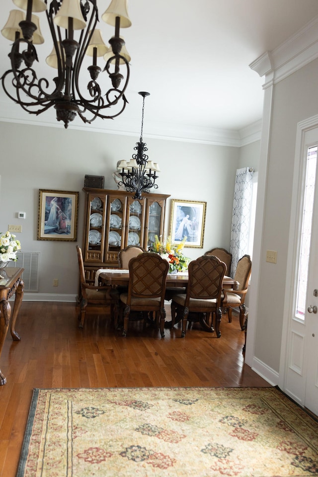 dining room with dark wood-type flooring, a notable chandelier, crown molding, and a healthy amount of sunlight