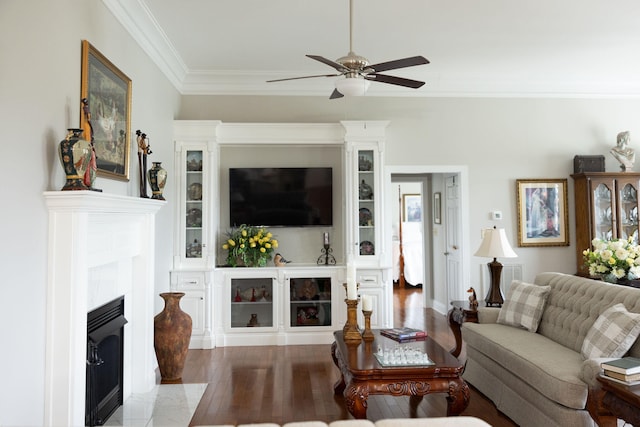 living room with crown molding, hardwood / wood-style flooring, a tile fireplace, and ceiling fan