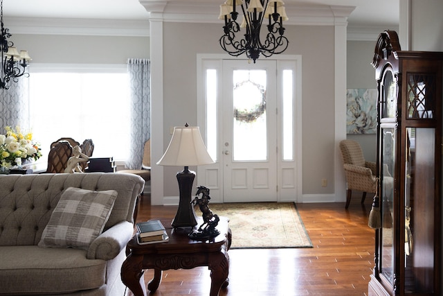 entrance foyer featuring wood-type flooring, ornamental molding, and a chandelier