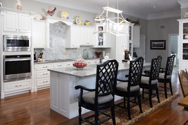 kitchen with a center island, stainless steel appliances, pendant lighting, a breakfast bar area, and dark hardwood / wood-style floors