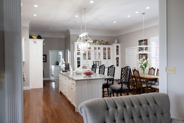 kitchen with white cabinetry, ornamental molding, dark wood-type flooring, pendant lighting, and a center island