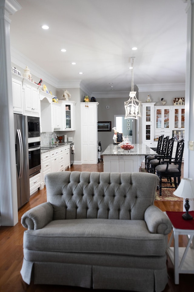 living room featuring a notable chandelier, ornamental molding, sink, and dark hardwood / wood-style flooring