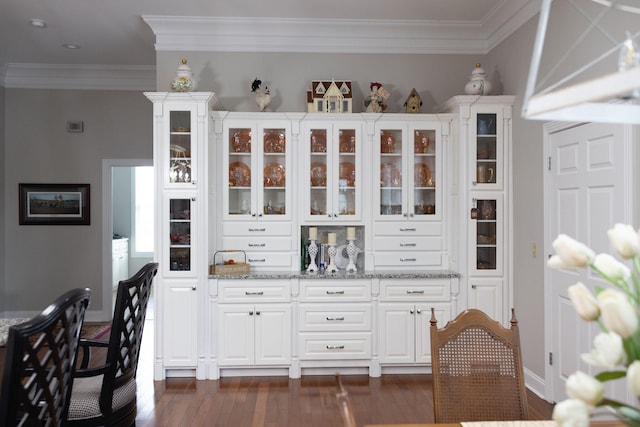 bar with ornamental molding, white cabinetry, light stone counters, and dark hardwood / wood-style flooring