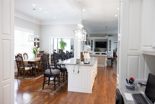 kitchen with a kitchen breakfast bar, white cabinetry, a center island, and pendant lighting