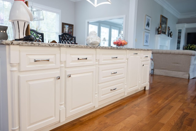 kitchen with white cabinetry, crown molding, a healthy amount of sunlight, and wood-type flooring