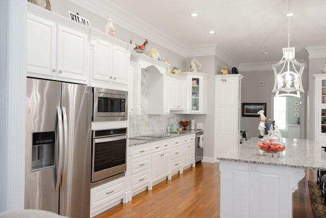 kitchen featuring light stone countertops, appliances with stainless steel finishes, white cabinetry, ornamental molding, and light hardwood / wood-style flooring