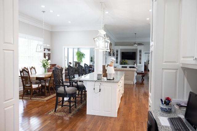 kitchen featuring hanging light fixtures, a kitchen breakfast bar, light stone countertops, dark hardwood / wood-style floors, and a center island