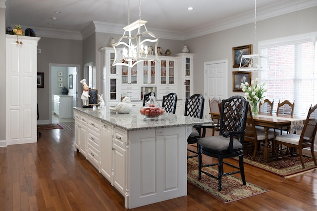 kitchen featuring a kitchen island, hanging light fixtures, crown molding, white cabinets, and dark hardwood / wood-style flooring