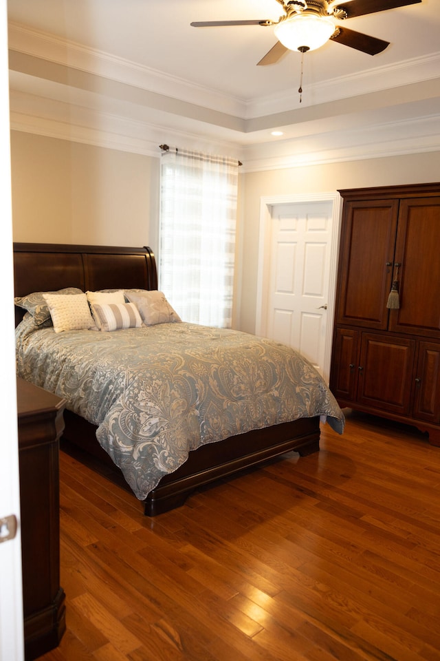 bedroom with dark wood-type flooring, crown molding, and ceiling fan