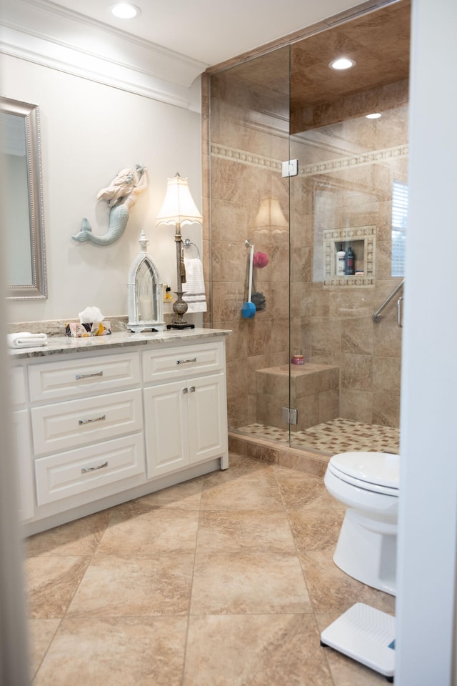 bathroom featuring toilet, a shower with shower door, vanity, and crown molding