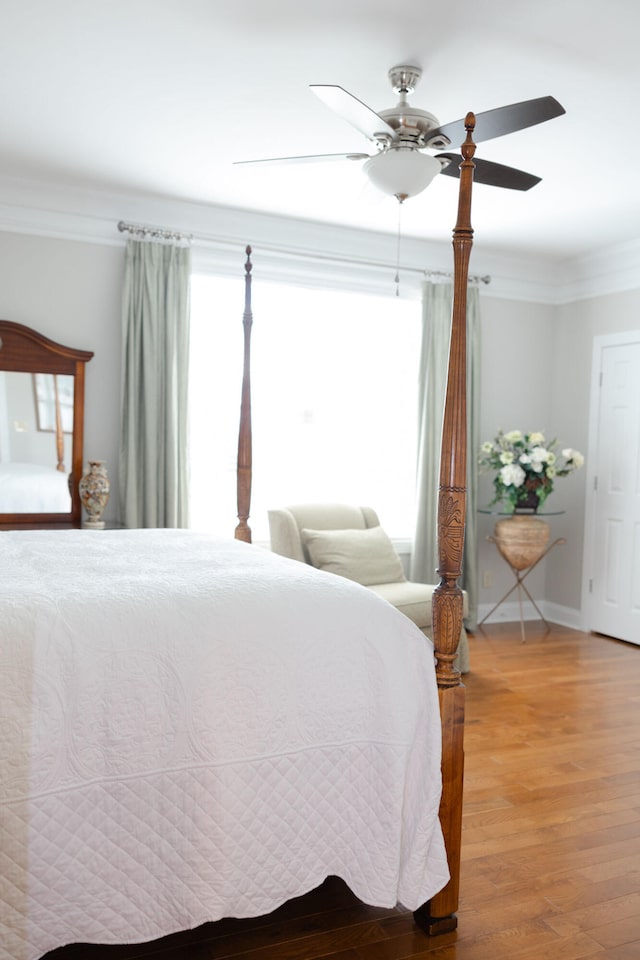 bedroom with crown molding, wood-type flooring, and ceiling fan