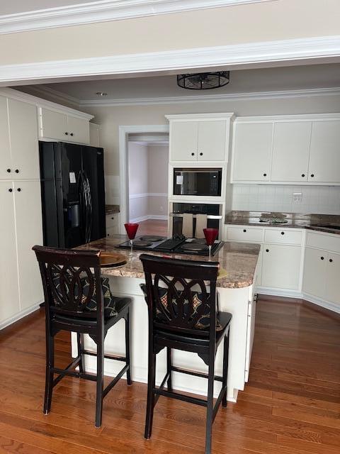 kitchen with a kitchen island, white cabinetry, crown molding, and black appliances