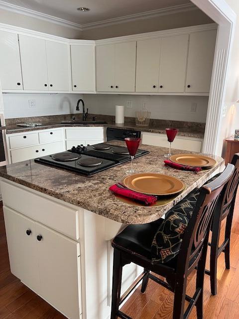 kitchen with an inviting chandelier, black appliances, sink, a kitchen island, and white cabinetry