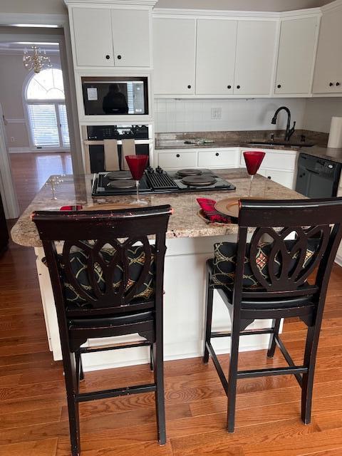 kitchen featuring white cabinetry, black stovetop, and crown molding