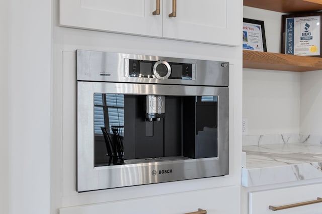 room details with light stone counters, oven, and white cabinets