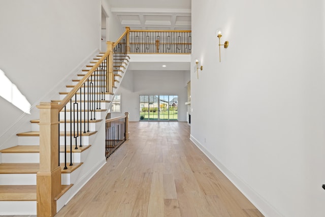 stairs featuring a towering ceiling, hardwood / wood-style floors, beam ceiling, and coffered ceiling