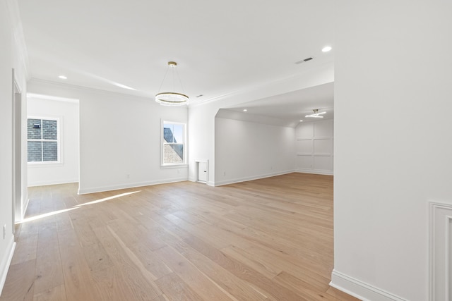 empty room with crown molding and light wood-type flooring