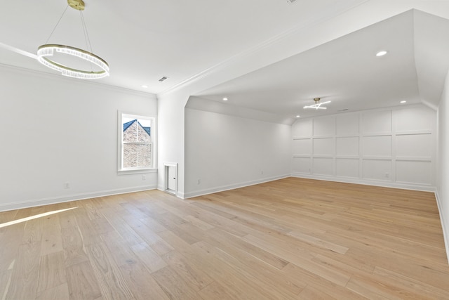 empty room with crown molding, light hardwood / wood-style flooring, and a chandelier