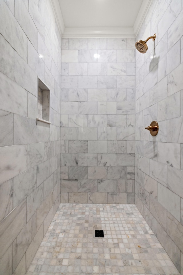 bathroom featuring a tile shower and ornamental molding