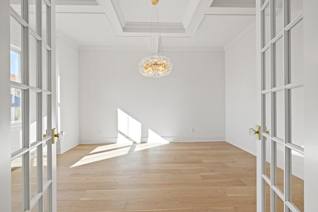 empty room featuring french doors, light hardwood / wood-style floors, crown molding, and an inviting chandelier