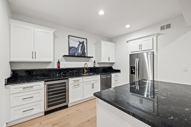 kitchen with white cabinetry, stainless steel appliances, and beverage cooler