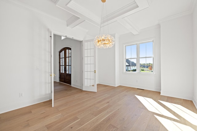 empty room with coffered ceiling, french doors, light hardwood / wood-style flooring, ornamental molding, and an inviting chandelier