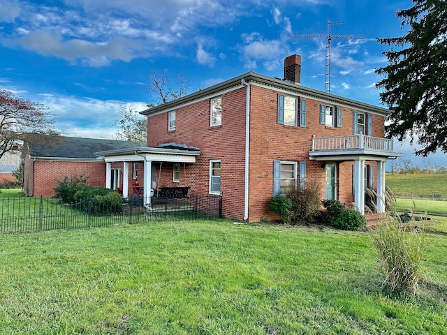 rear view of property featuring a balcony and a lawn